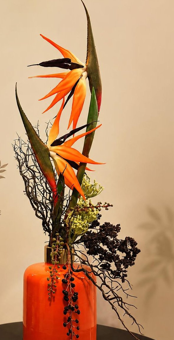 Tall bird of paradise arrangement in a bright orange ceramic vase, by Bloom by Sindra